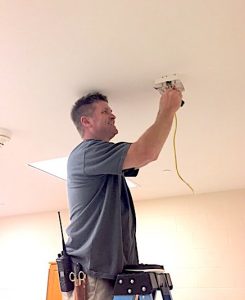 Worker installs wireless acess point on the ceiling at Horton Hall.
