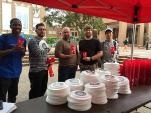 Five students show the freebies they picked up at Adobe Red Tent Day.