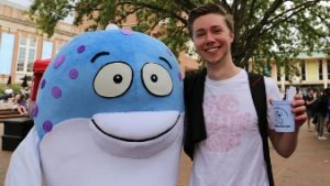 A student poses with person wearing a fish costume
