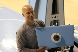 Assistant Coach Mike Schall holds an IP camera in Carmichael Arena