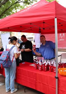 Greg Neville shows off Adobe cup while staffing the Adobe tent at the tech fair in the Pit