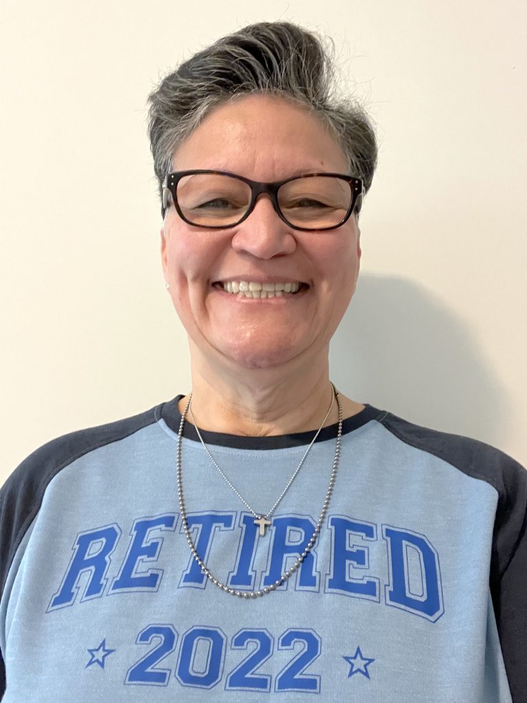 Ingrid Camacho smiles wearing T-shirt that says "Retired 2022"