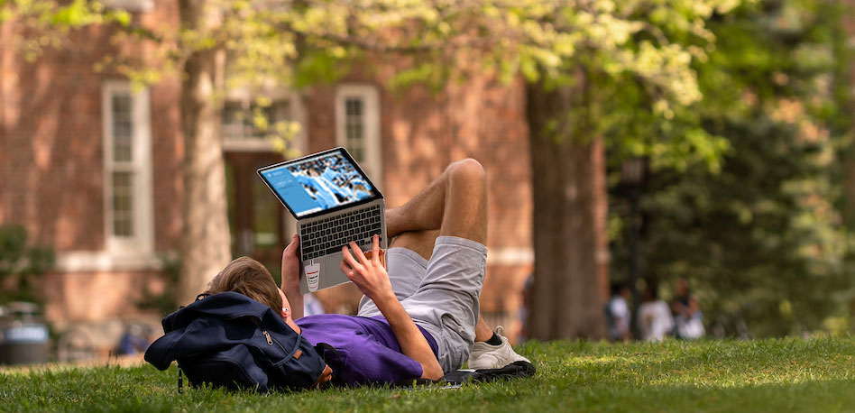 Student looking at laptop on Polk Place