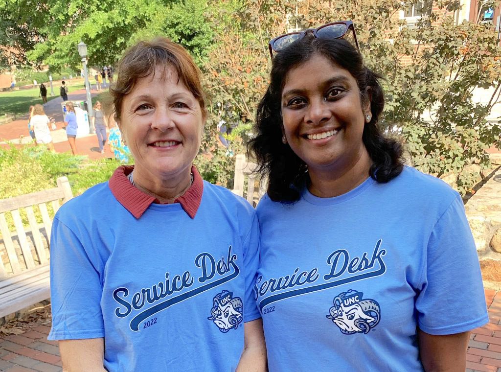 Wearing Service Desk T-shirts, Cheri Beasley and Brenda Carpen pose together outside on campus.