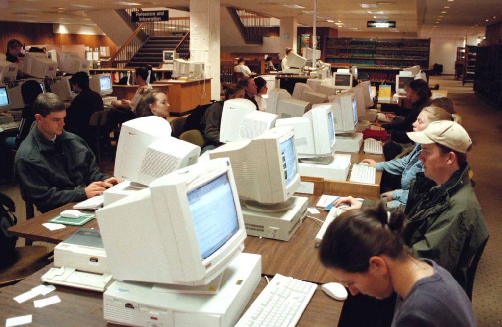 Students study at a row of older computers in the Undergraduate Library