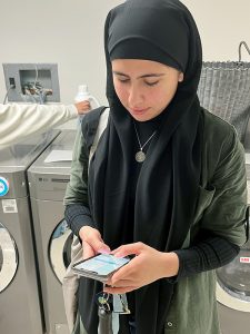 A dorm resident uses the laundry app on her smartphone in the laundry room.
