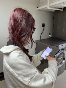 A woman uses the Washlava app on her phone to select a dryer