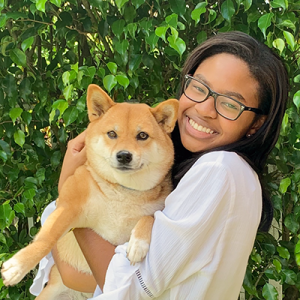 Jessica Walker smiles widely while holding her dog, a shiba inu
