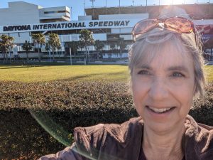 On a sunny day, Jenny Williams takes a selfie in from of Daytona International Speedway