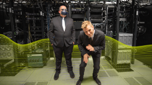 Podcast hosts Michael Williams and Charlie Mewshaw, dressed as proverbial Men in Black, clown around in a server room