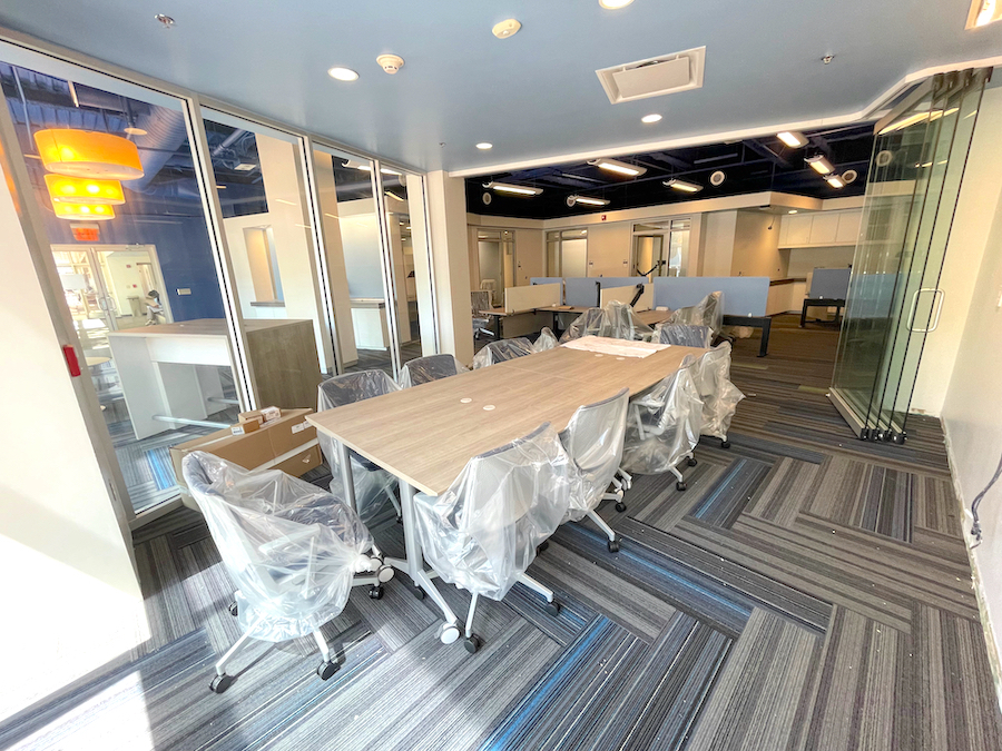 The new open and airy conference room in-progress, with chairs covered in plastic surrounding a conference table