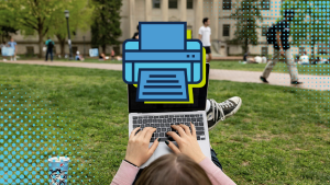 An over the shoulder view of a student using her laptop on the quad. A giant blue printer icon pops over her screen