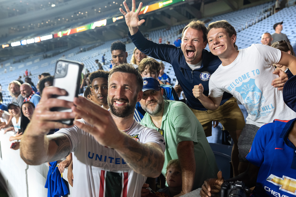 A soccer player takes a selfie with excited fans