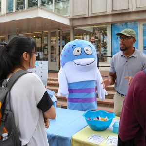 A goofy fish mascot in front of Student Stores