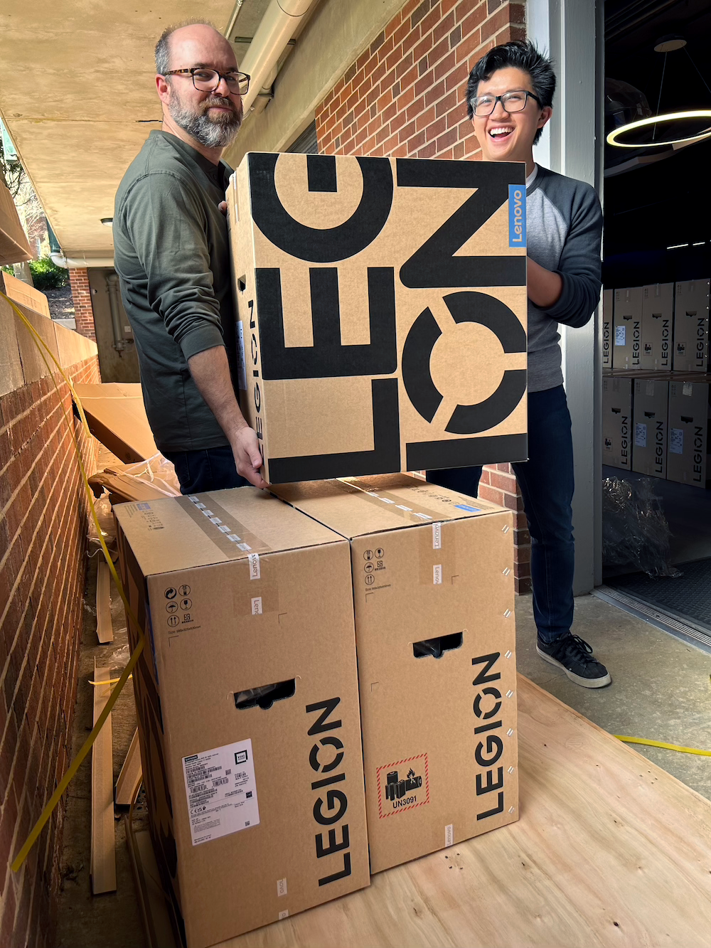 ResNET staffers Phil Young and Alex Ho carry a Lenovo Legion box into the Gaming Arena
