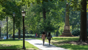 View of McCorkle Place during the summer. A few visitors walk along the brick pathway near the Caldwell monument